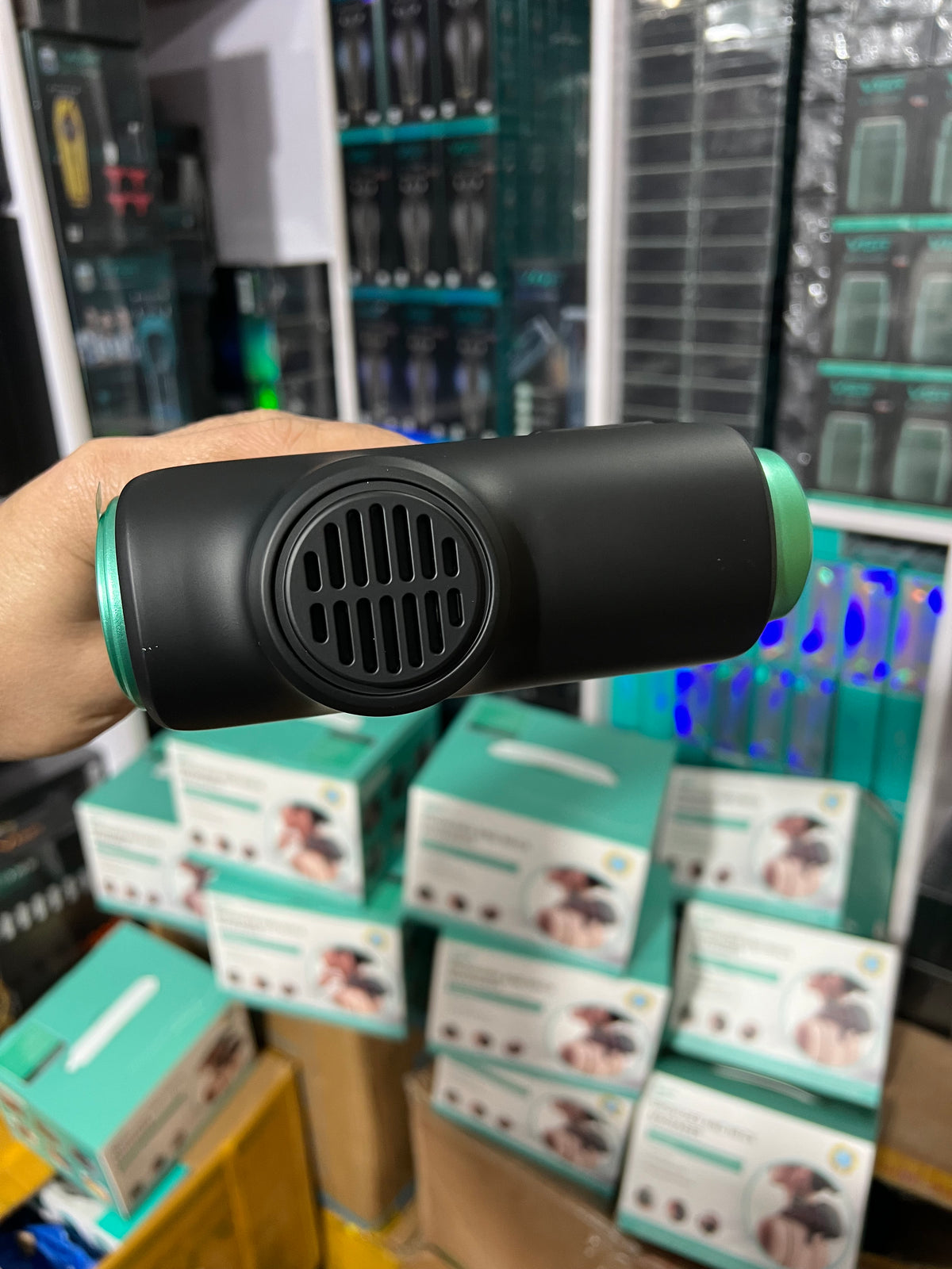 Black handheld device with green accents held in front of a store shelf.