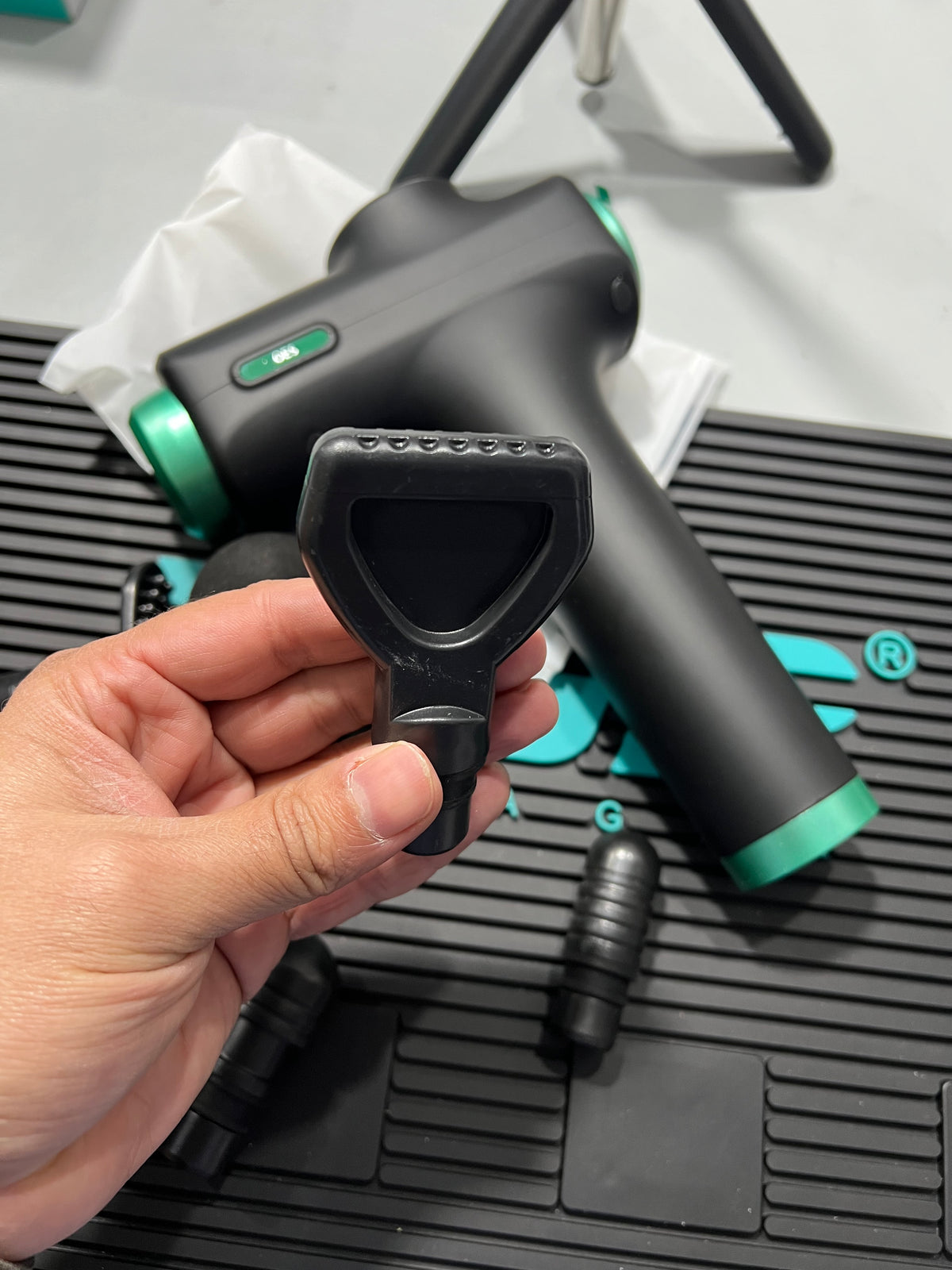 Hand holding a black and green garden hose nozzle against a white background