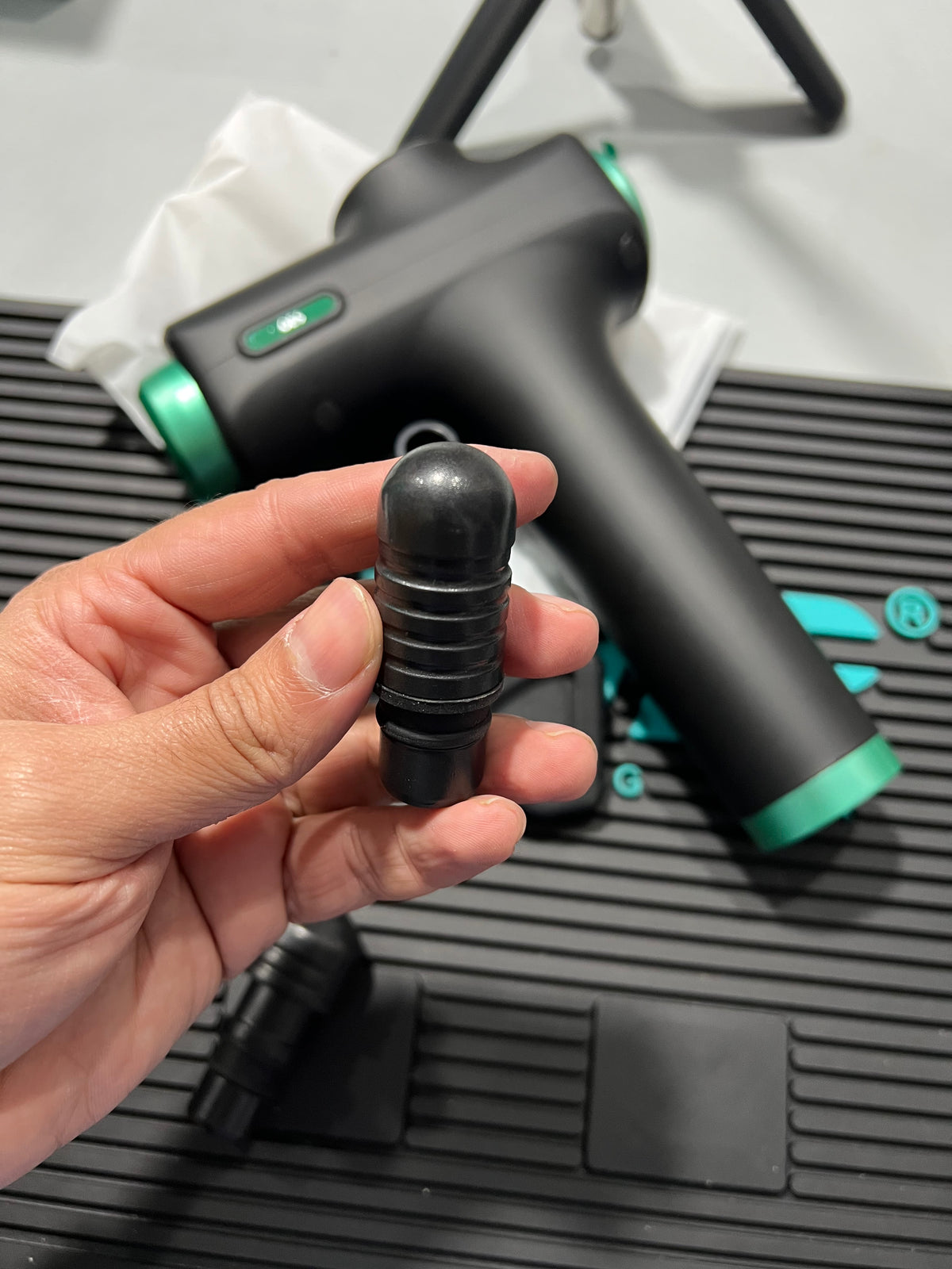 Hand holding a black and green tool component with a blurred background