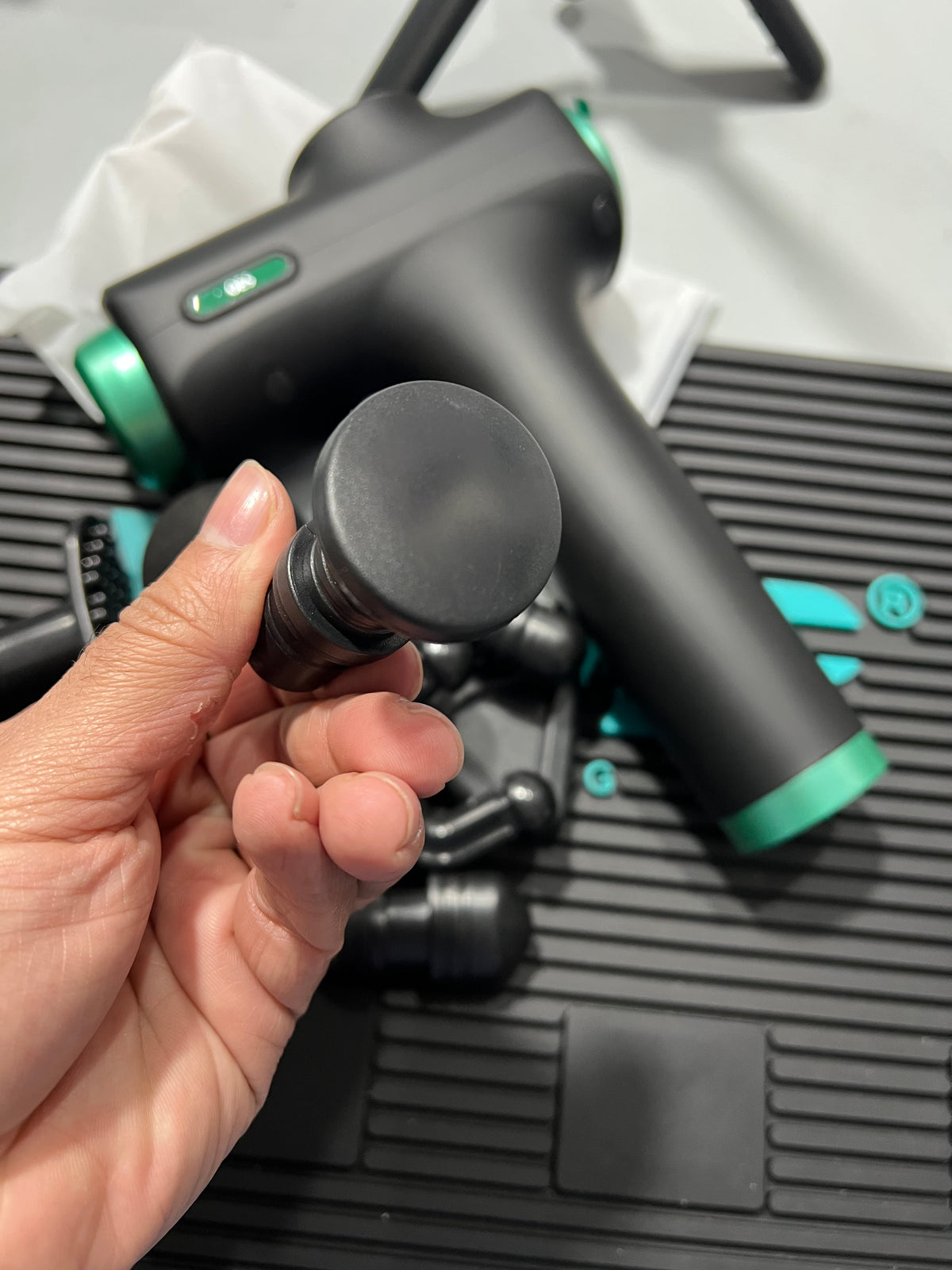 Hand holding a black and green vacuum attachment with a blurred background
